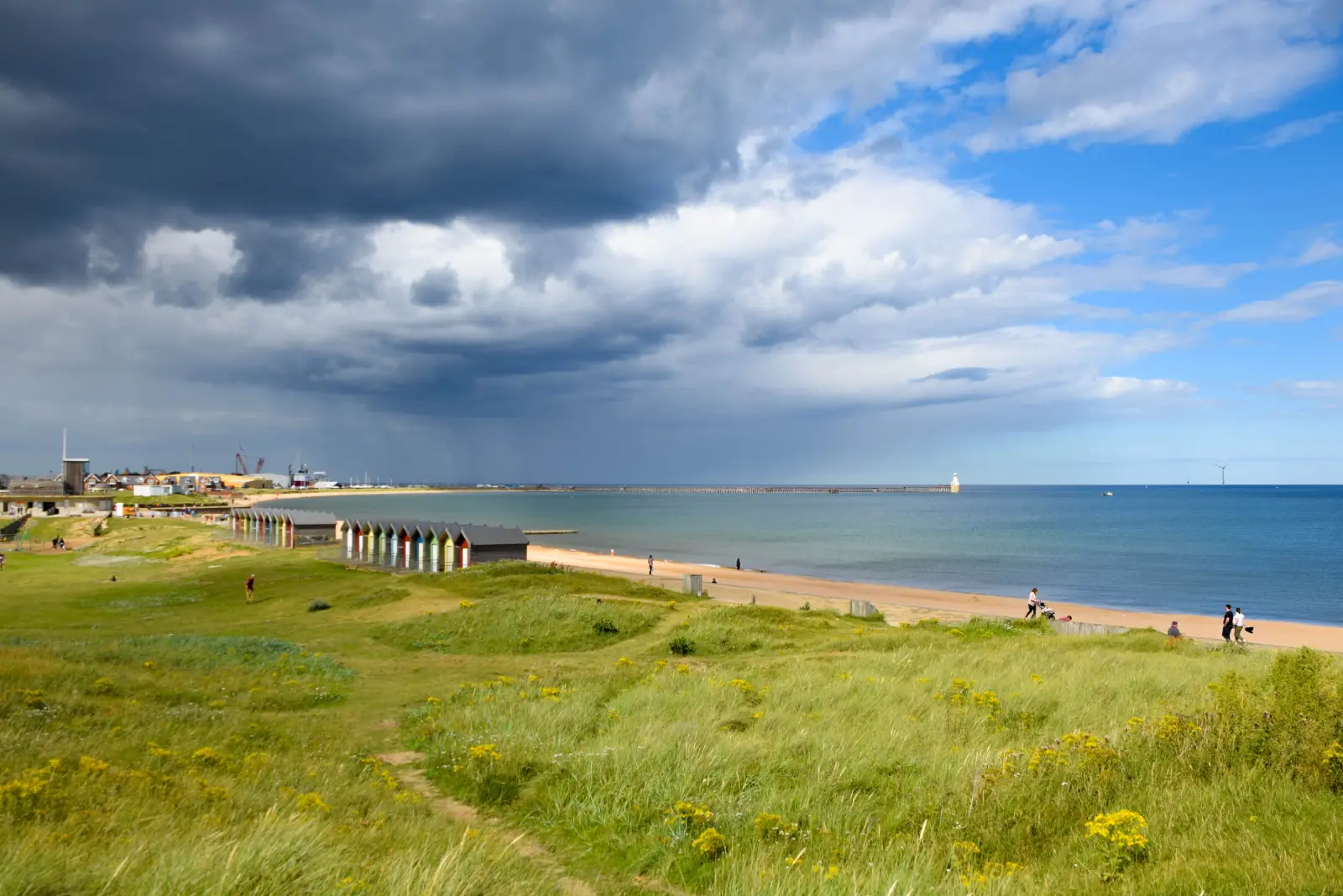 Blyth beach and colourful beach huts beneath dramatic clouds on the Northumberland coast